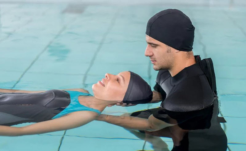 Man assisting floating woman in pool